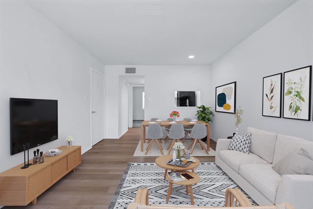 A living room with a white couch, a coffee table, and a television.
