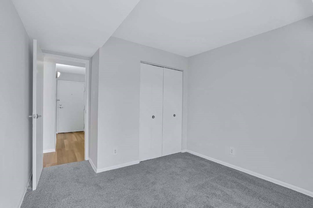 an empty bedroom with white walls and wood floors