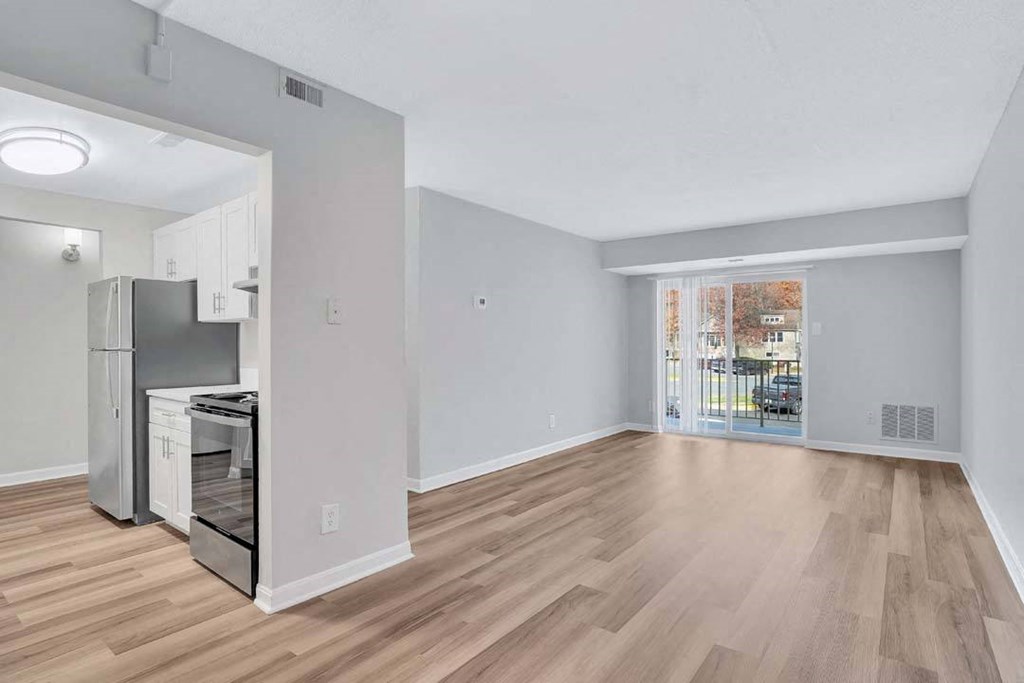a living room and kitchen with a door to a balcony