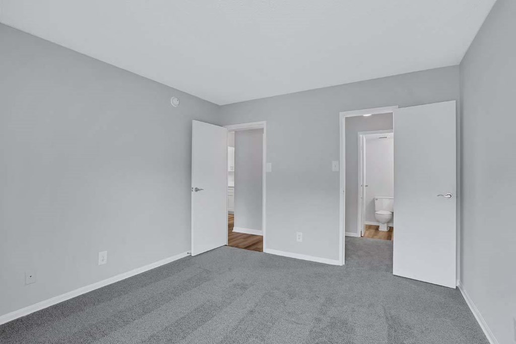 a bedroom with a carpeted floor and a door to a bathroom