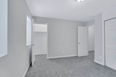 A spacious room with grey carpeting and white walls.