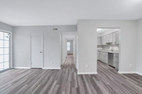 A spacious room with wood flooring and white walls.