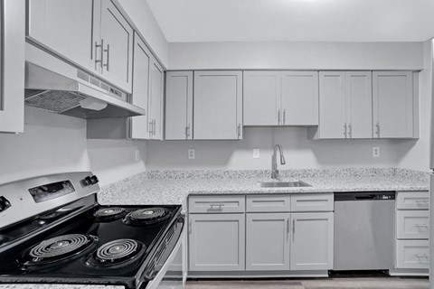 A kitchen with white cabinets and a black stove top.