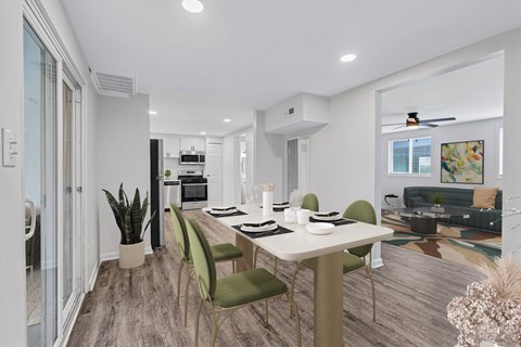 A modern dining room with a white table and green chairs.