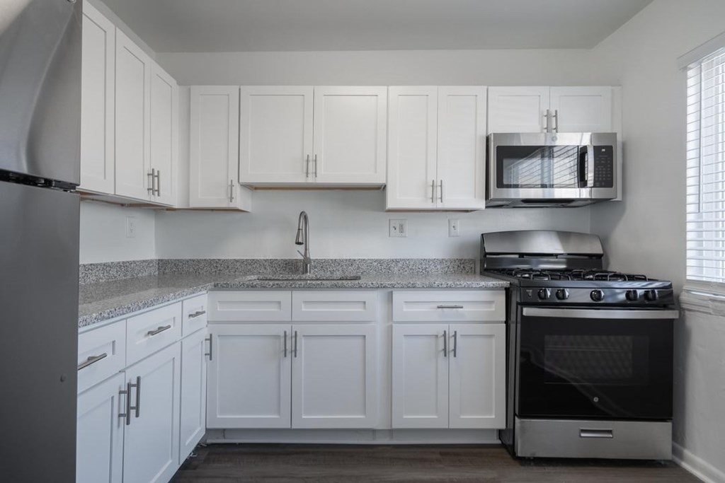A kitchen with white cabinets and a black refrigerator.