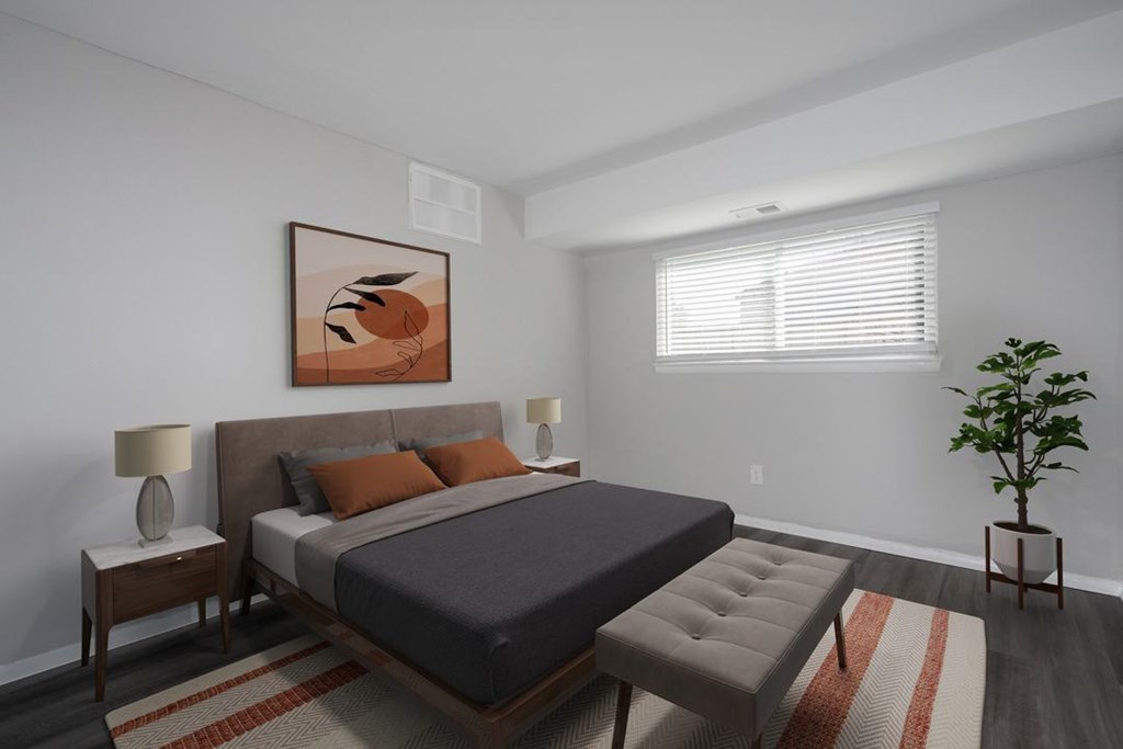 A bedroom with a bed, nightstands, and a plant.