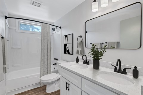 A white bathroom with a toilet, sink, and mirror.