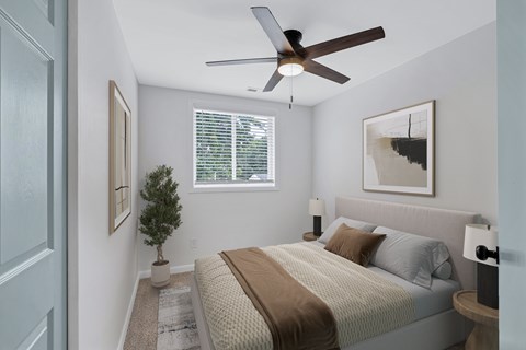 A bedroom with a bed, a ceiling fan, and a small tree.