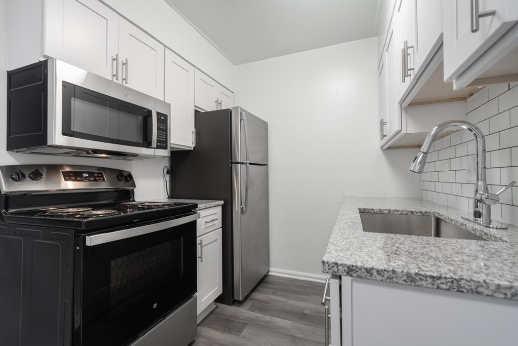 A kitchen with black appliances and white cabinets.