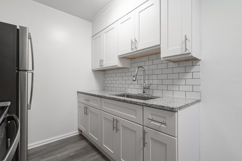 A kitchen with white cabinets and a black refrigerator.