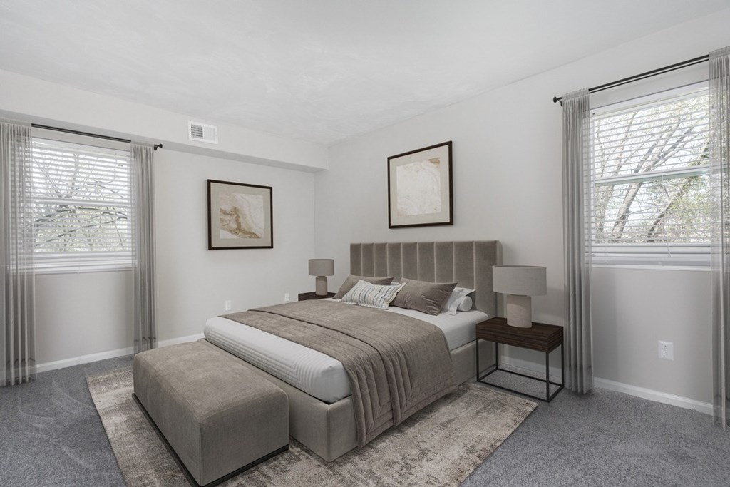 A bedroom with a large bed and two framed pictures on the wall.