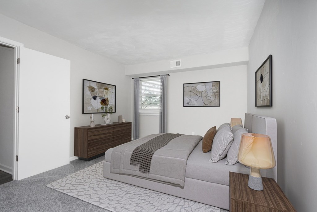 A bedroom with a bed, nightstand, and artwork on the wall.