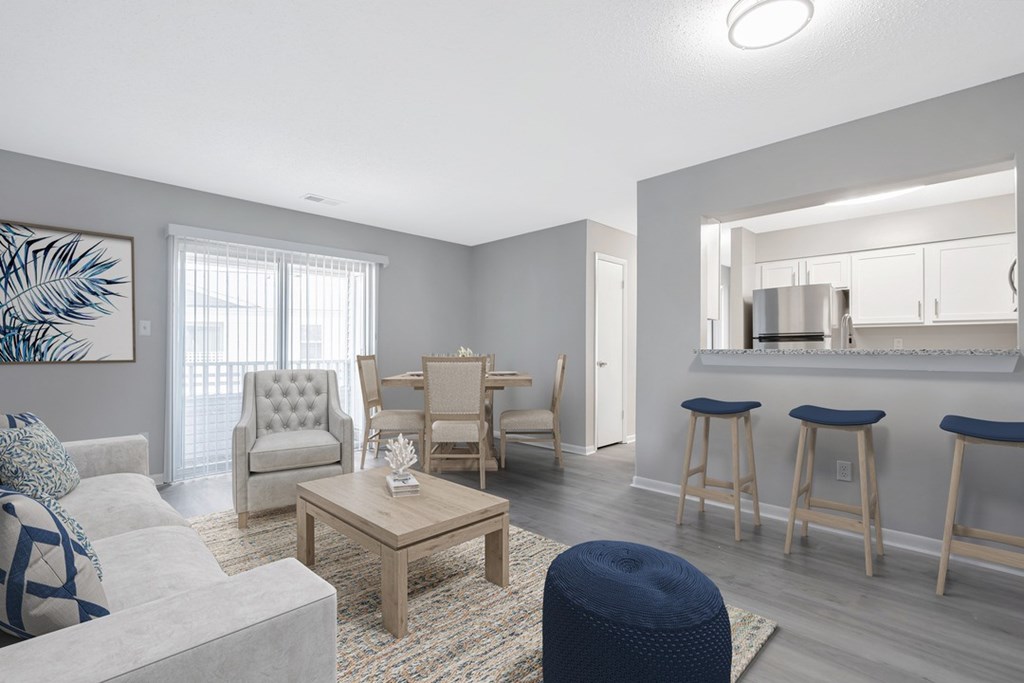 A living room with a grey couch, a coffee table, and a dining area in the background.