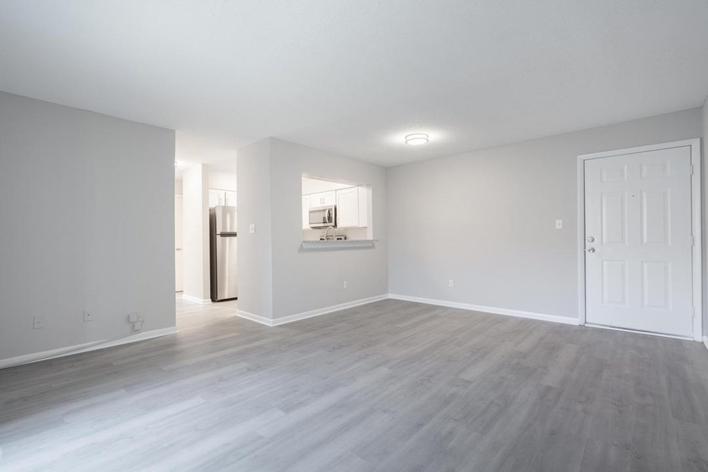 A spacious room with a white door and a window.