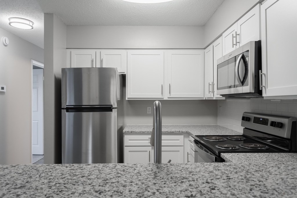A kitchen with a refrigerator, microwave, oven, and stove.