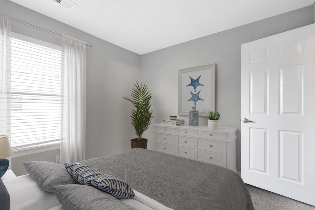 A bedroom with a bed, nightstand, and a painting on the wall.
