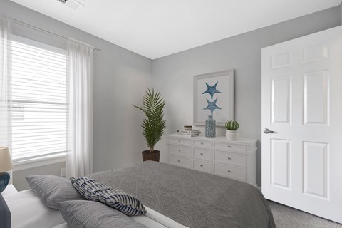 A bedroom with a bed, nightstand, and a painting on the wall.