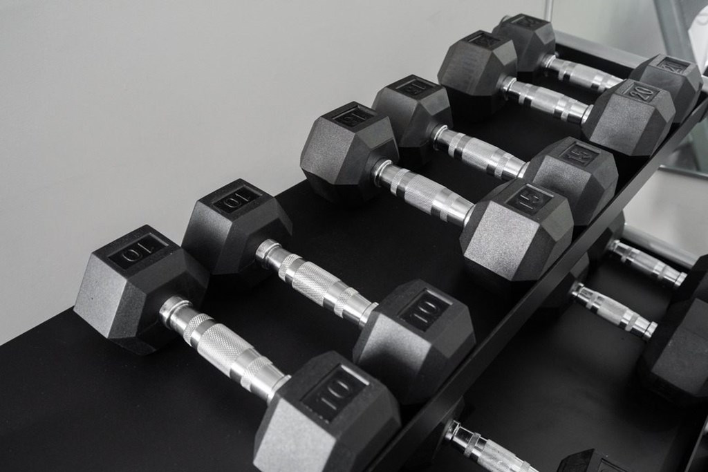 A set of dumbbells are arranged on a black surface.