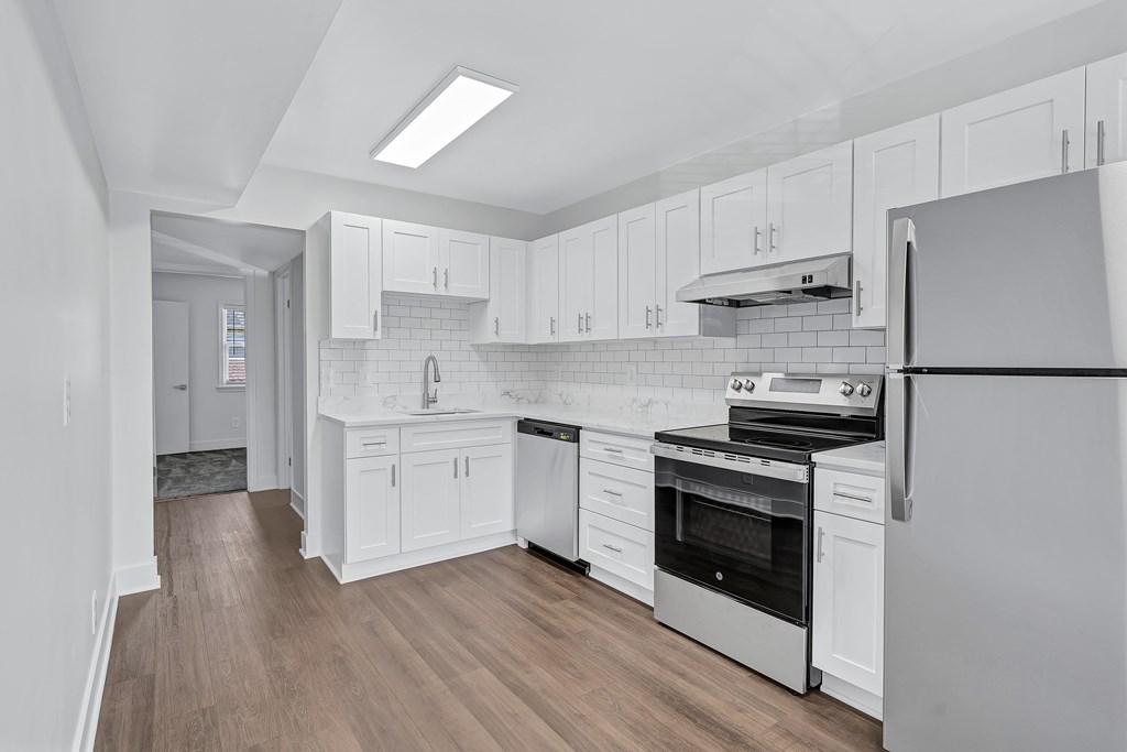 A modern kitchen with white cabinets and stainless steel appliances.