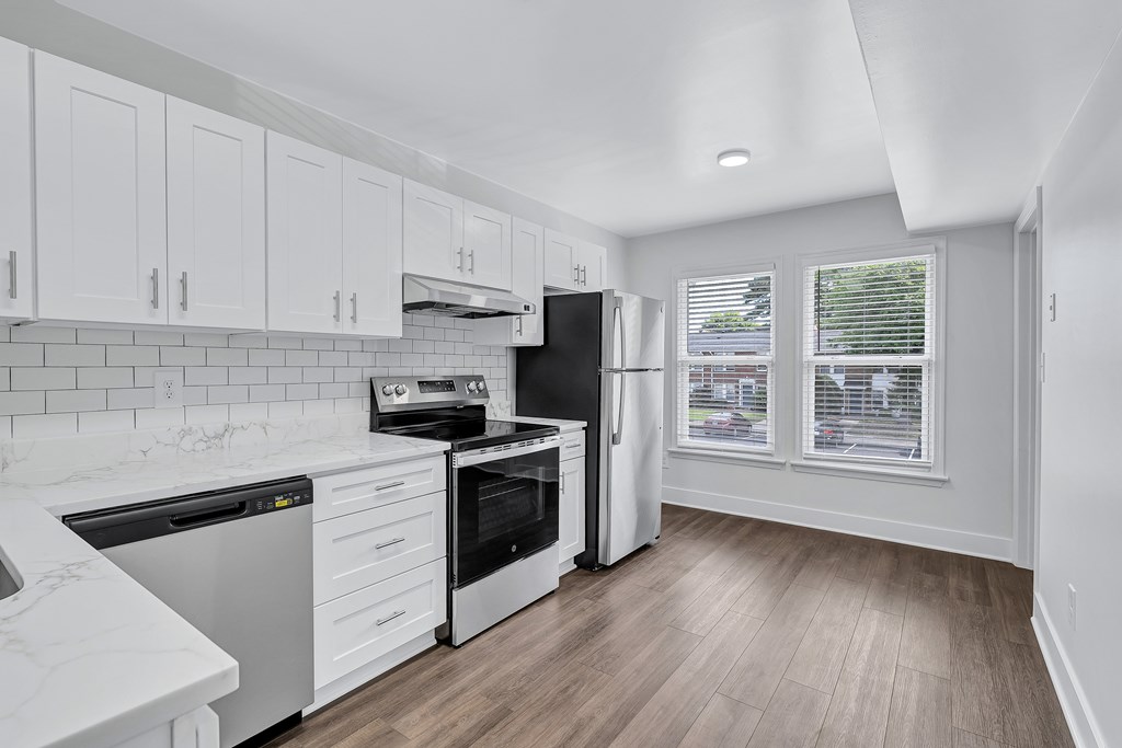 A kitchen with white cabinets and a black refrigerator.
