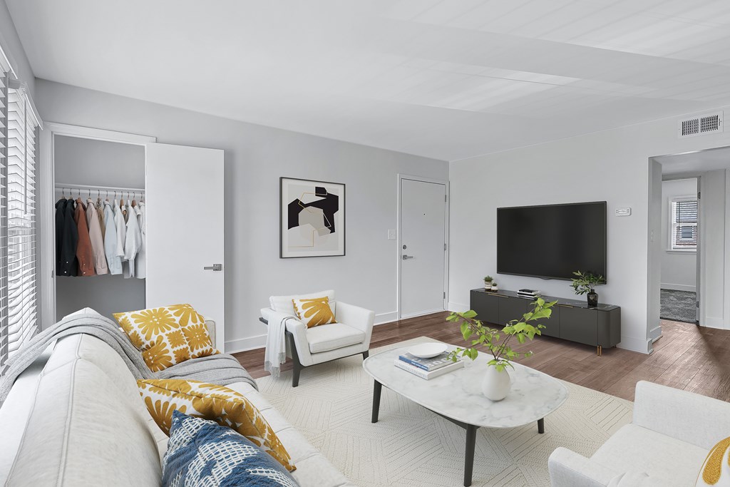 A living room with a grey couch, a white chair, a coffee table, and a television.
