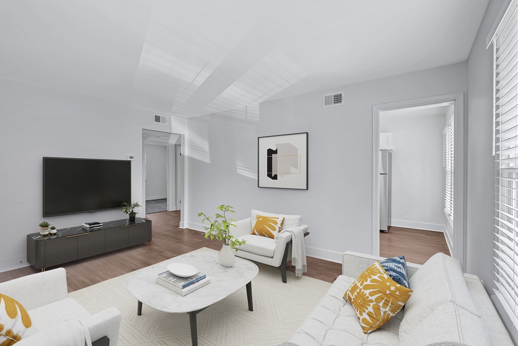 A living room with a white couch, a coffee table, and a television.