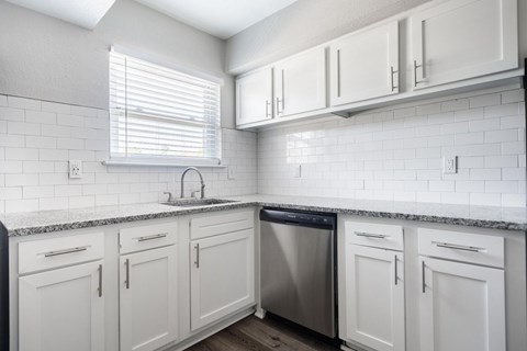 A kitchen with white cabinets and a black dishwasher.