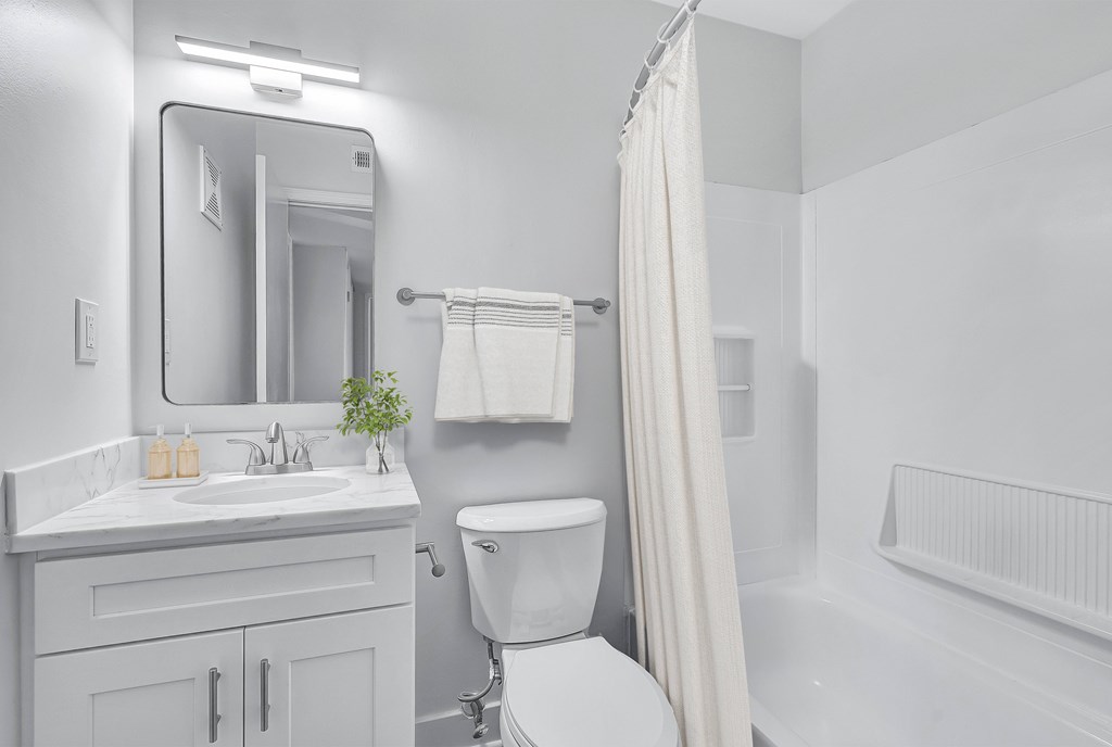 A white bathroom with a toilet, sink, and bathtub.