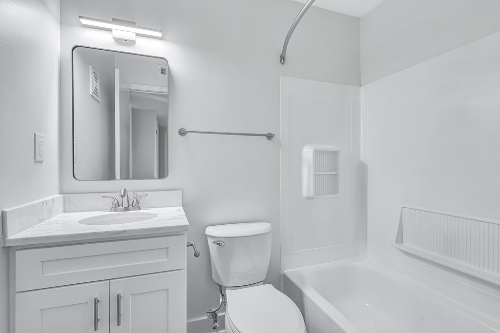 A white bathroom with a toilet, sink, and bathtub.
