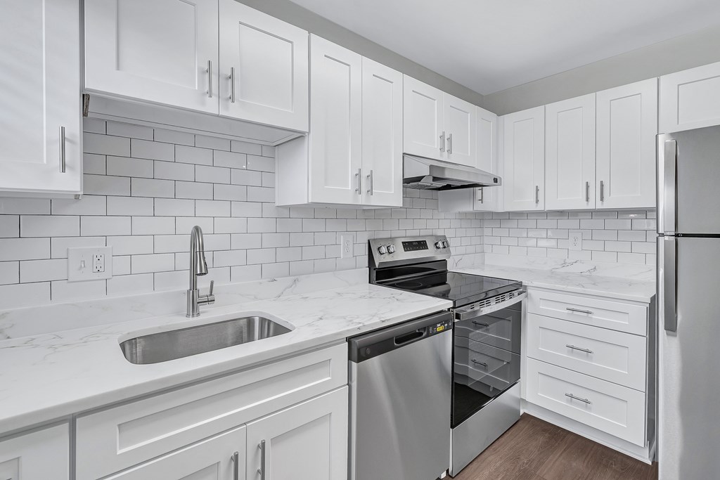 A kitchen with white cabinets and a marble countertop.