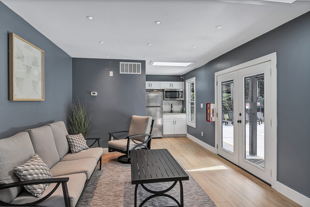 A modern living room with a grey sofa, a black table, and a framed picture on the wall.
