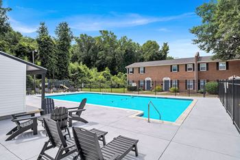 A pool surrounded by trees and chairs.