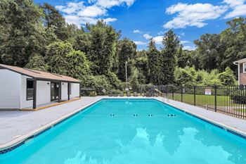 A swimming pool surrounded by trees and a building.