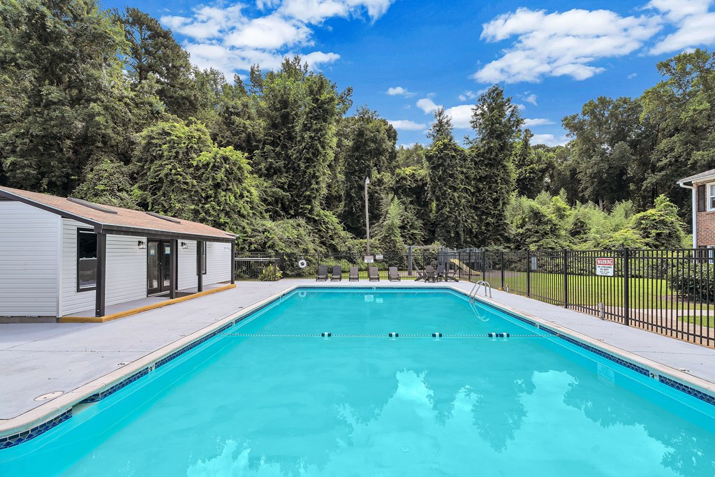 A swimming pool surrounded by trees and a building.