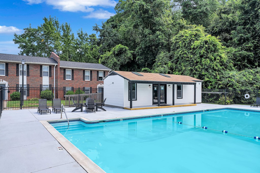 A swimming pool in front of a house with a white exterior.