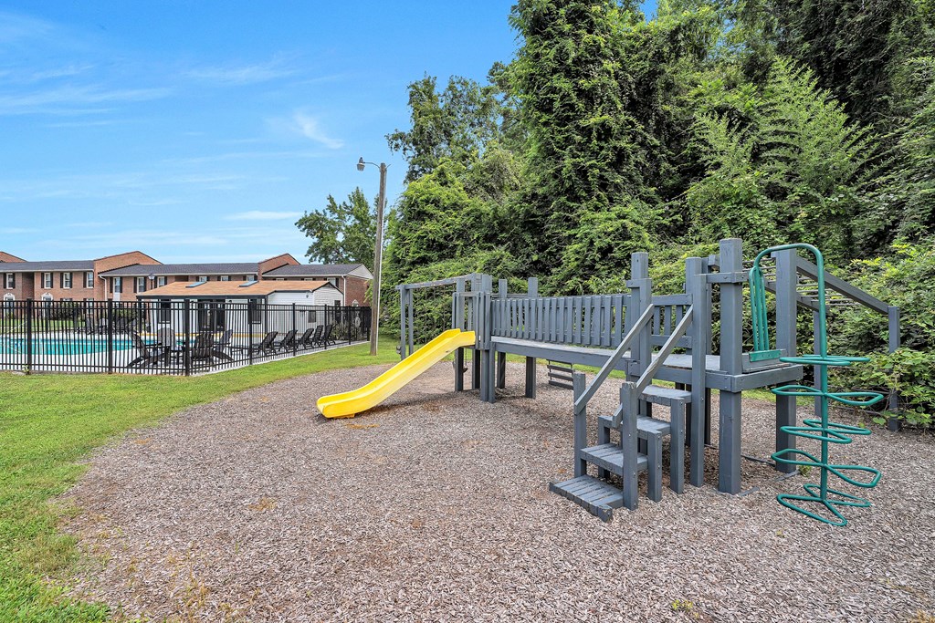 A playground with a yellow slide and a green spring rider.