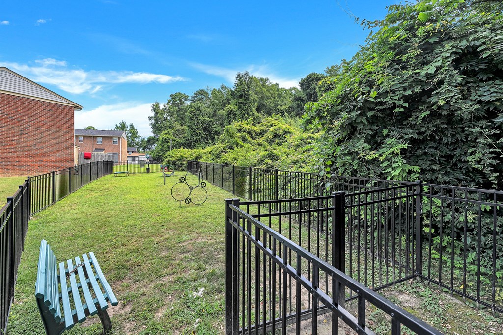 A black metal fence surrounds a green park area.