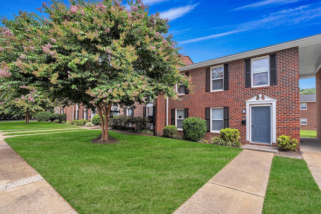 A tree with pink flowers is in front of a brick building.