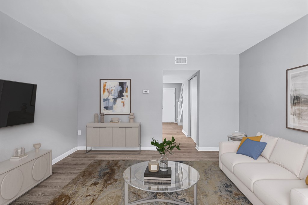 A living room with a white couch and a glass coffee table.