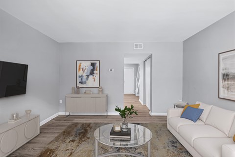A living room with a white couch and a glass coffee table.
