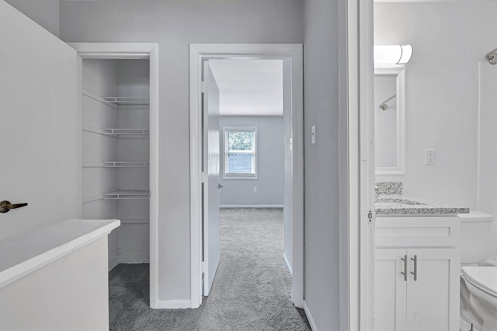A white bathroom with a tub, sink, and a walk-in closet.