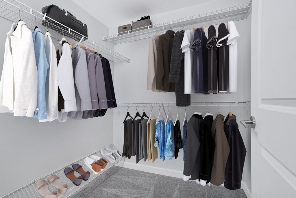 a walk in closet with a rack of clothes and shoes