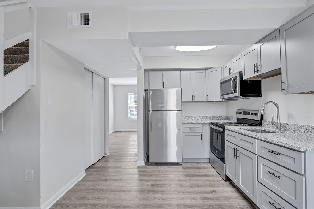 A kitchen with a refrigerator, microwave, and oven.