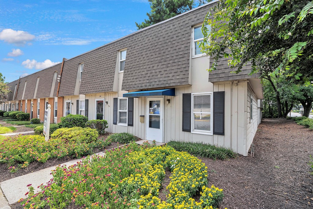 A building with a grey roof and white walls with a garden in front.