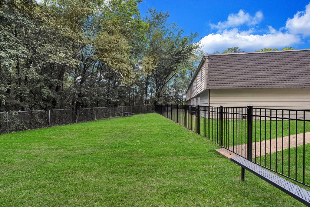 A black metal fence surrounds a green lawn.