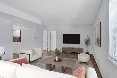 A living room with a white couch, a wooden coffee table, and a flat screen TV mounted on the wall.