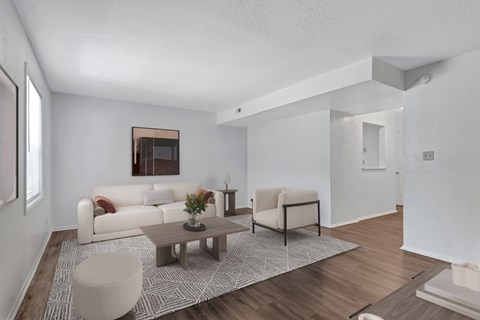 A living room with a white couch, a coffee table, and a chair.