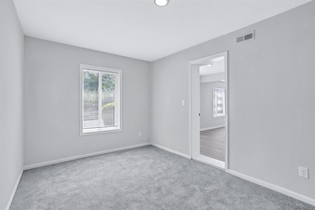 an empty bedroom with a mirror and a door to a hallway