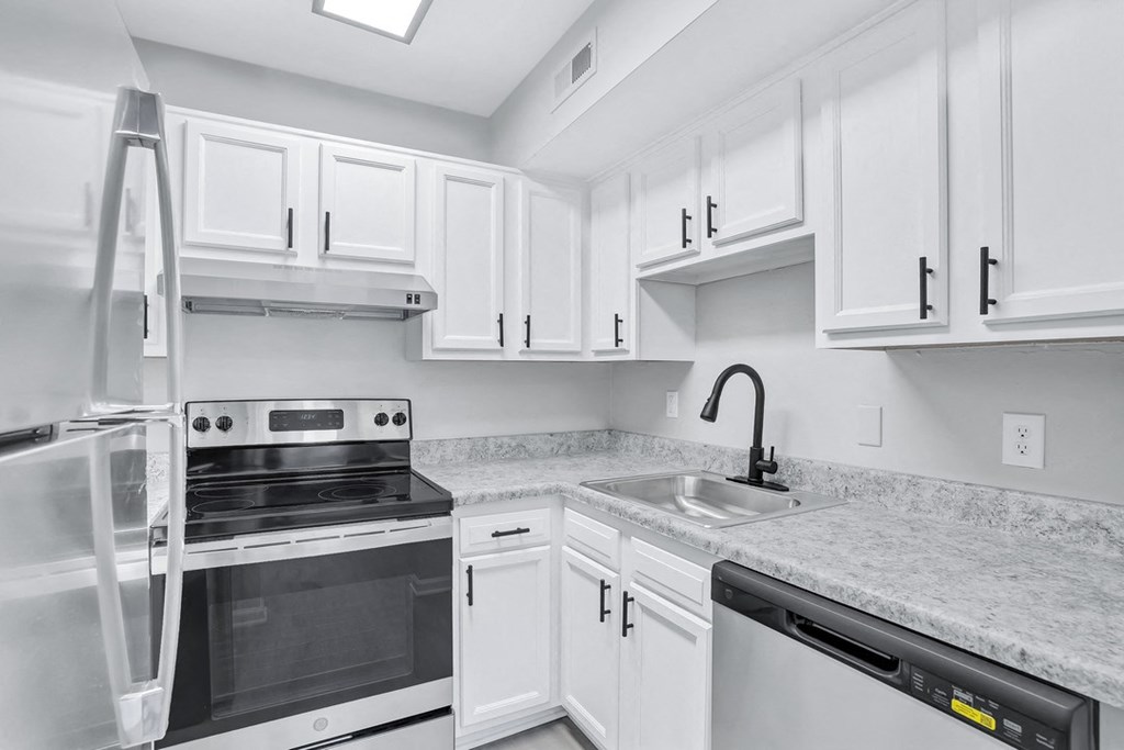 a white kitchen with white cabinets and black appliances