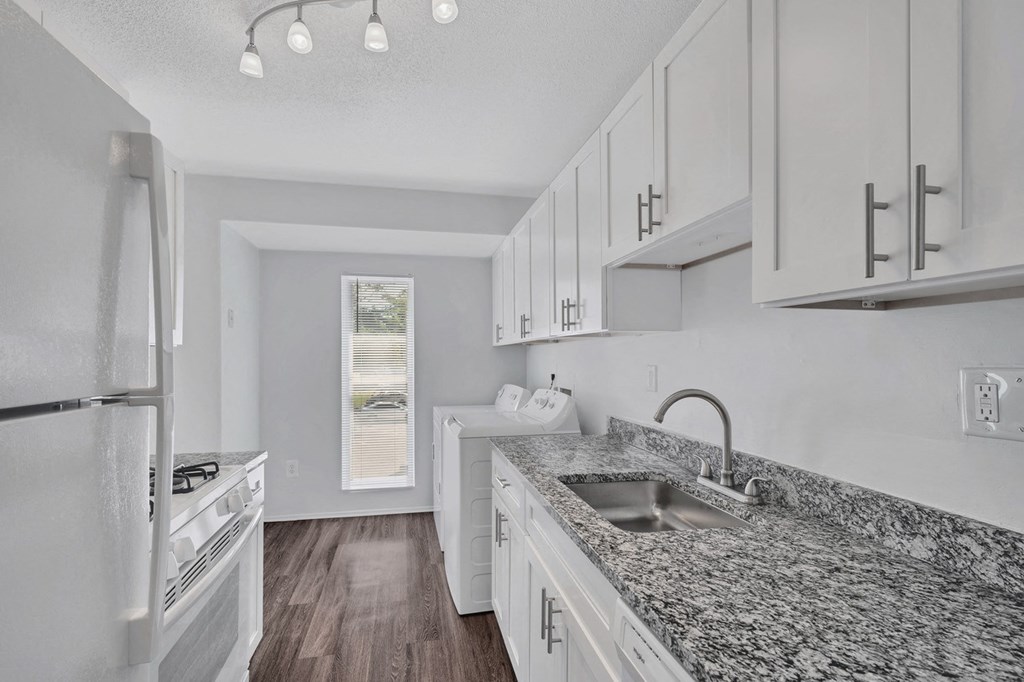 a kitchen with white cabinets and granite counter tops and a sink
